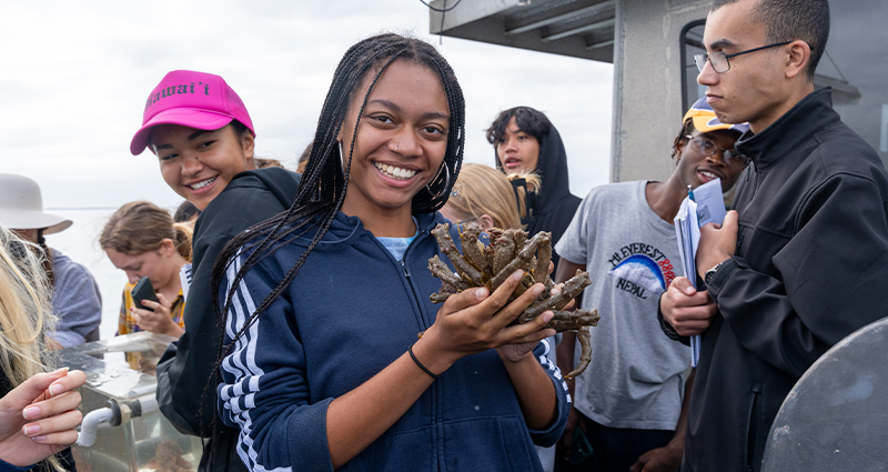 LMU female student holding crab on a boat